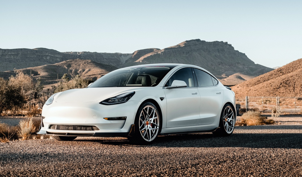 Белый автомобиль Tesla Model 3 Volta 2019 года на фоне гор 
