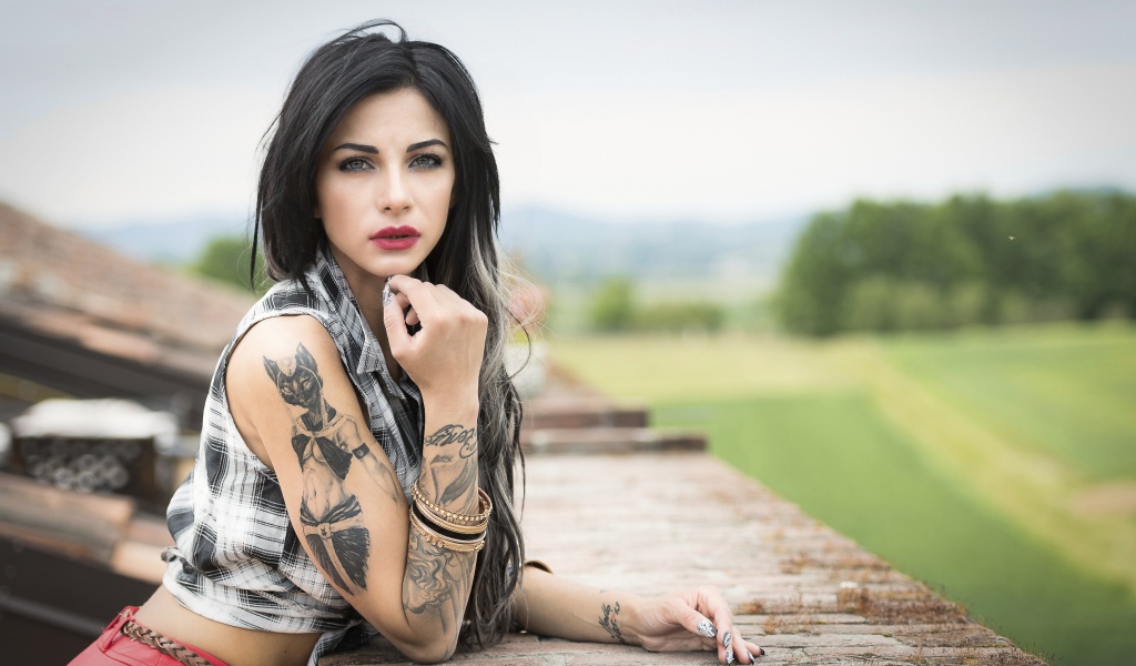 Молодая девушка брюнетка с татуировками на руках