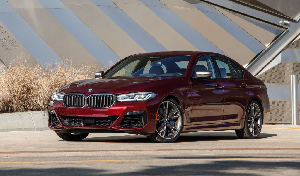 Бордовый седан BMW M550i XDrive, 2021 года у здания