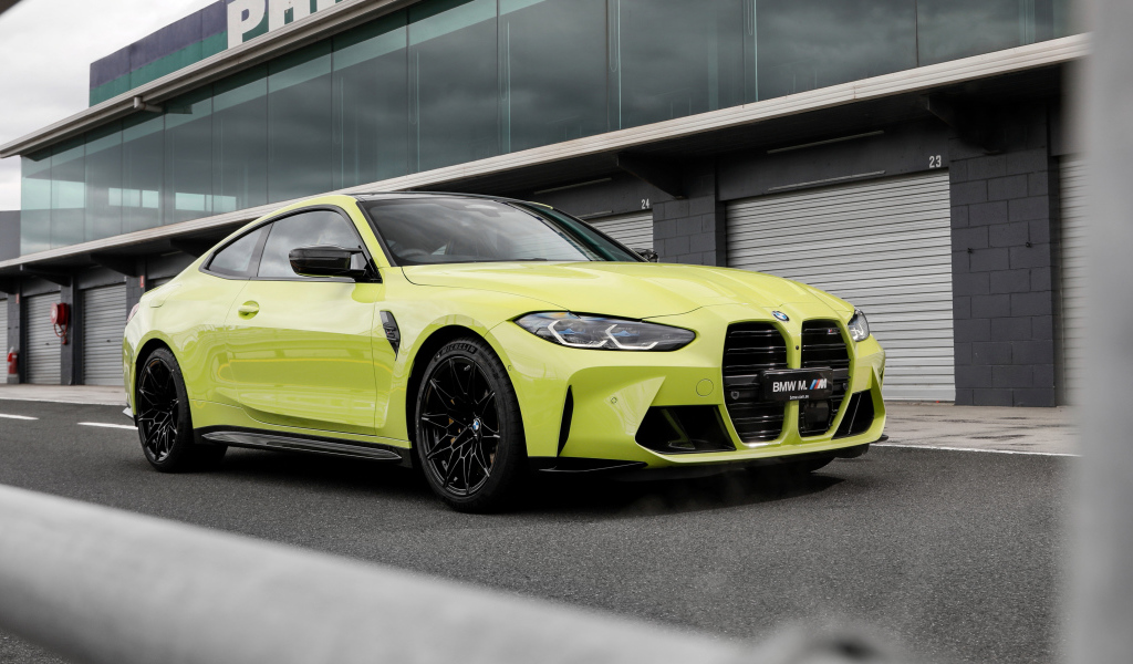 Желтый автомобиль BMW M4 Competition 2021 года у здания