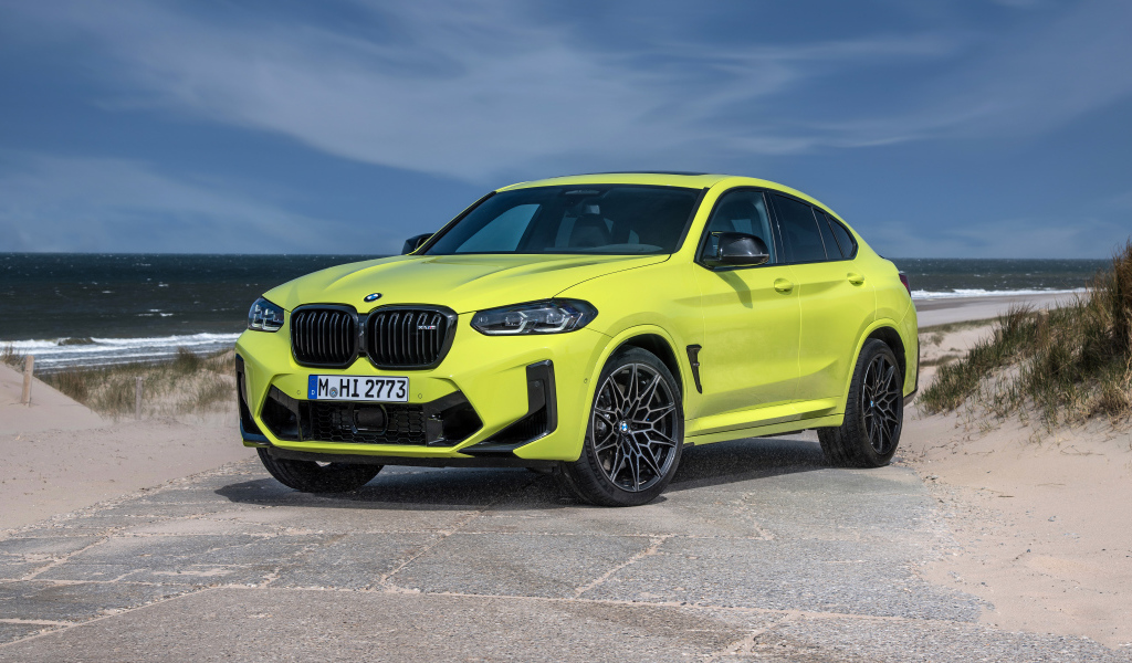 Желтый автомобиль BMW X4 M Competition 2021 года на фоне моря