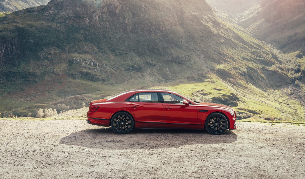 Красный автомобиль Bentley Flying Spur V8 2020 года у горы 