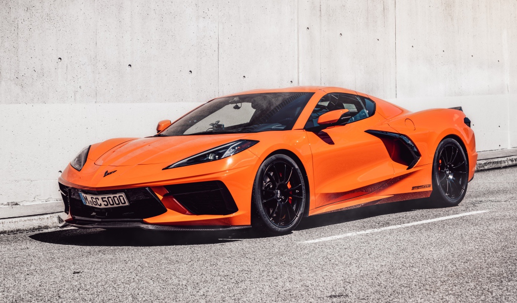 Оранжевый Chevrolet Corvette 2021 года на фоне серой стены