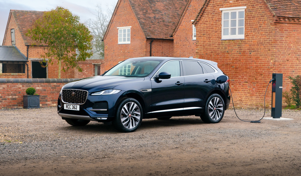 Черный дорогой автомобиль Jaguar F-Pace P400e AWD 2021 года, на заправке