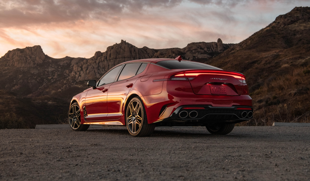 Красный автомобиль Kia Stinger GT, 2022 года в горах вид сзади