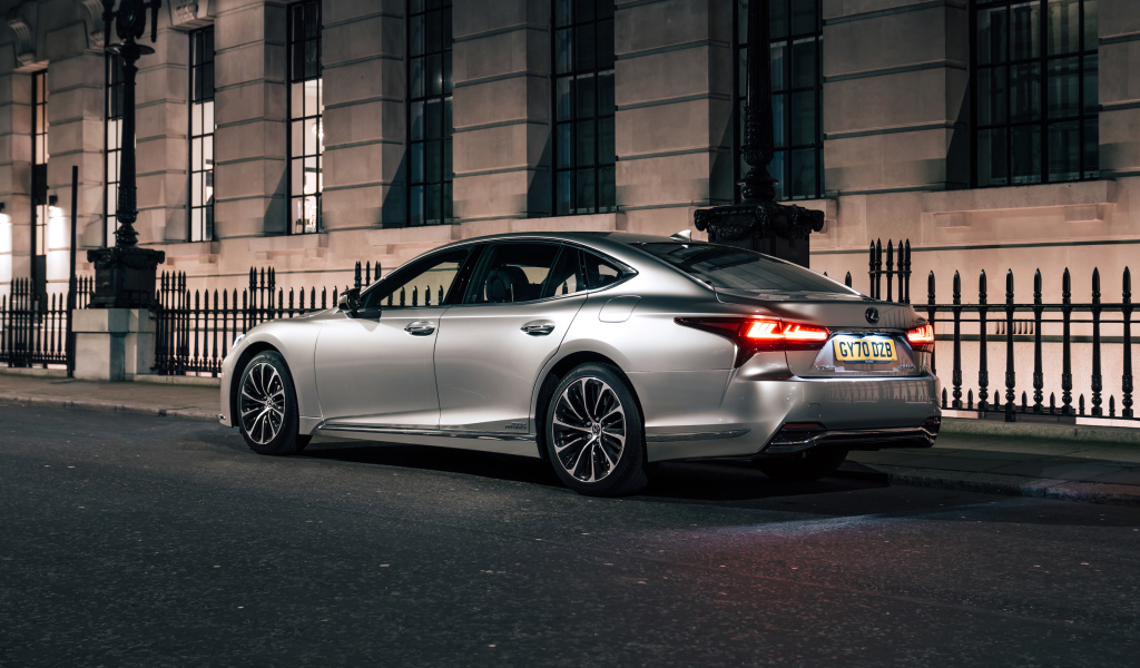 Серебристый автомобиль Lexus LS 500h 2021  года вид сзади