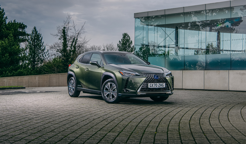 Зеленый автомобиль Lexus UX 300e 2021 года у стеклянной стены