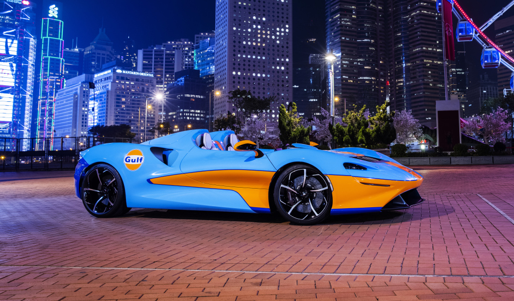 Автомобиль McLaren Elva Gulf Theme, 2021 года на фоне города