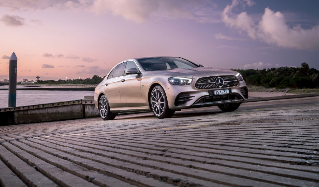 Серебристый автомобиль Mercedes-Benz E 300 E AMG Line 2021 года у реки