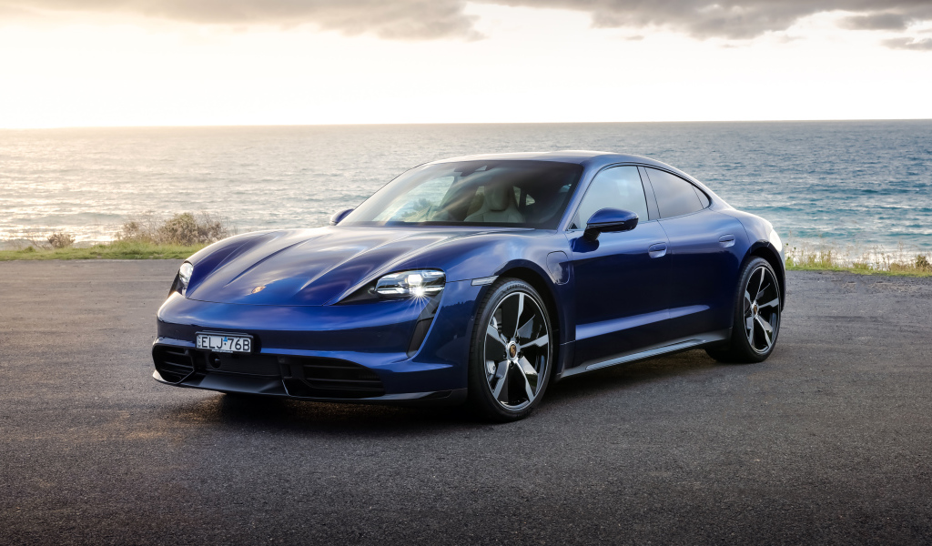 Синий автомобиль Porsche Taycan Turbo у моря