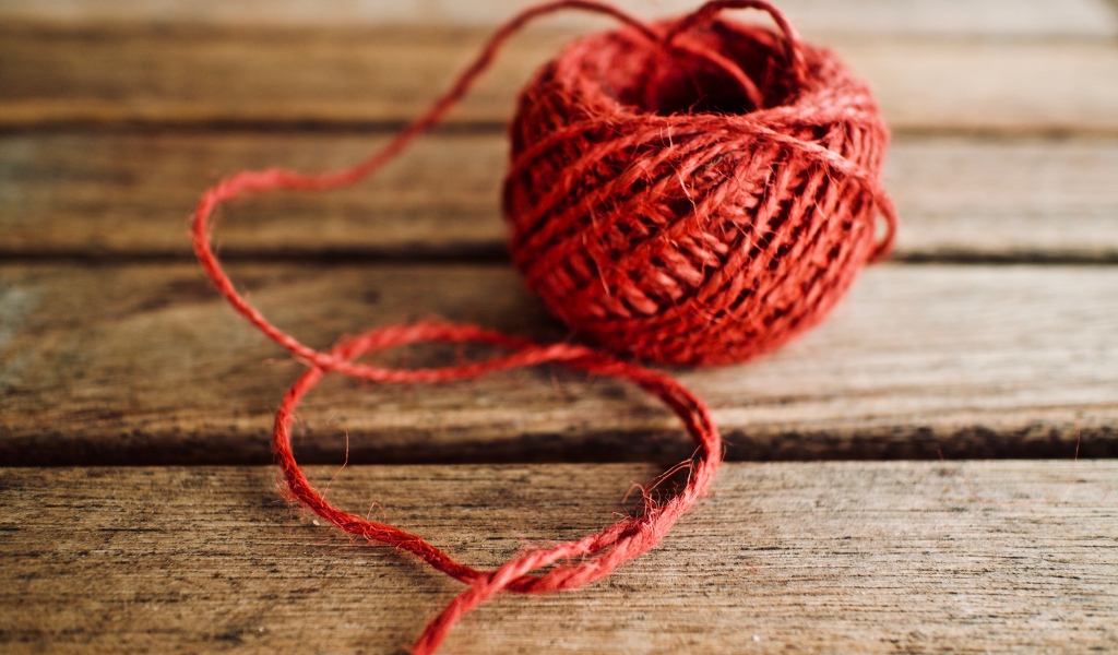 Клубок красной пряжи на деревянном столе 