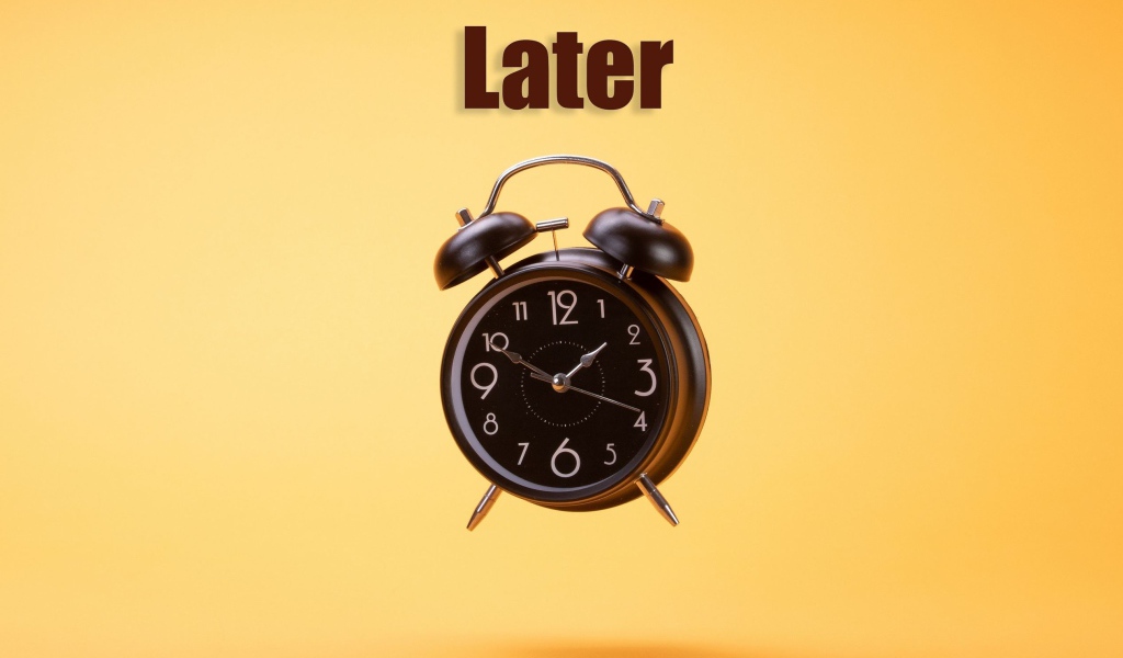 Большой черный будильник на желтом фоне 