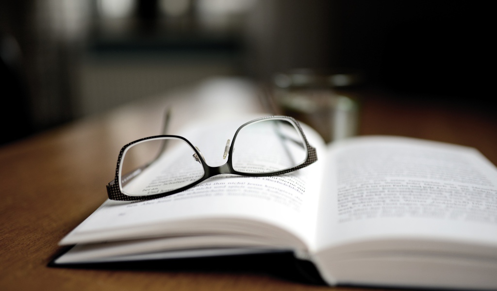 Черные очки лежат на книге 