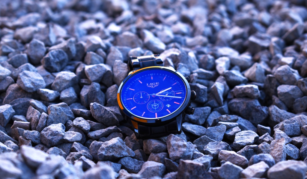 Голубые наручные часы лежат на камнях