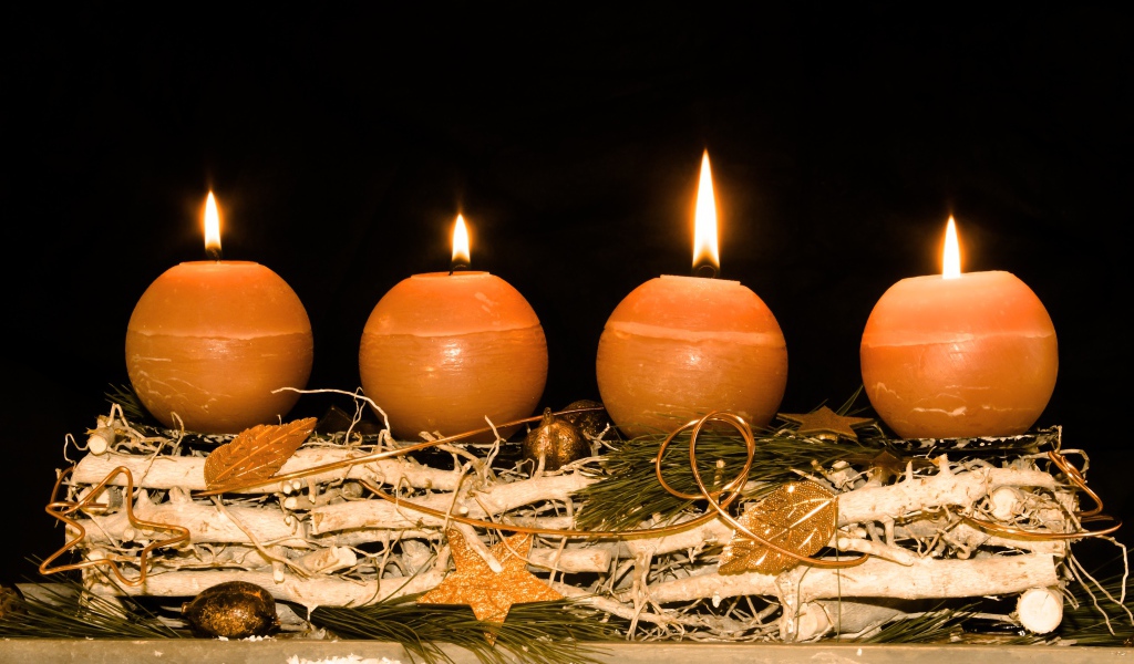Четыре круглые зажженные свечи на черном фоне