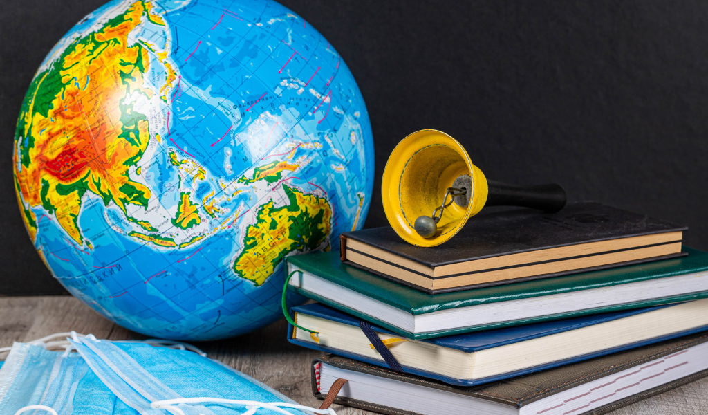 Глобус, книги, колокольчик и медицинские маски 