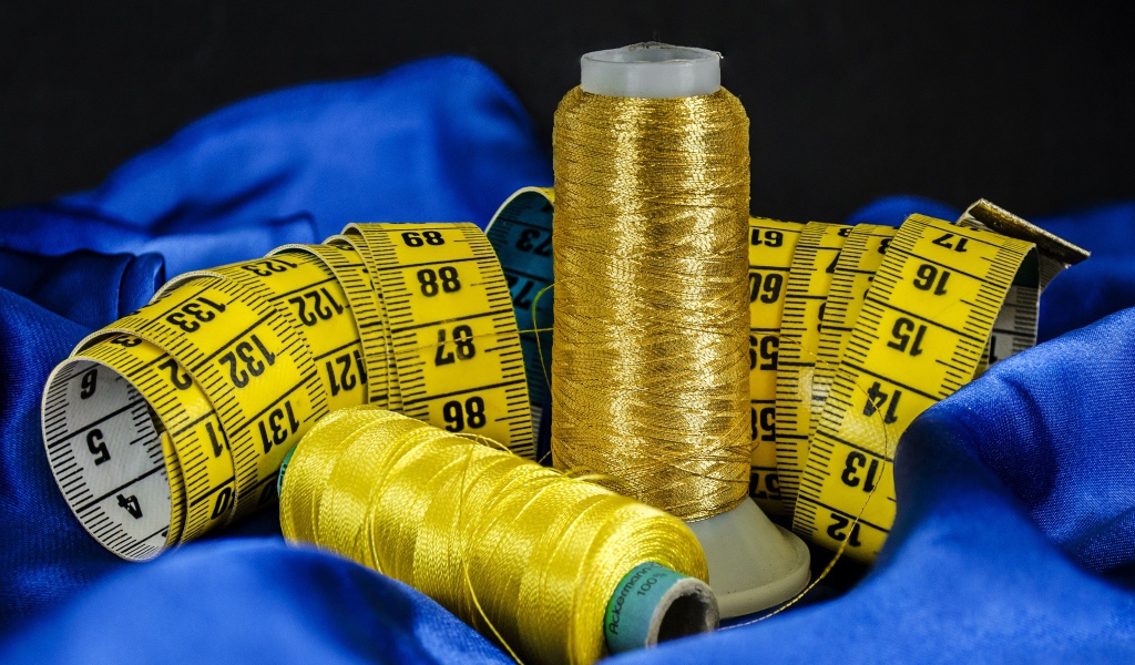 Золотые нитки и сантиметр на голубой ткани 