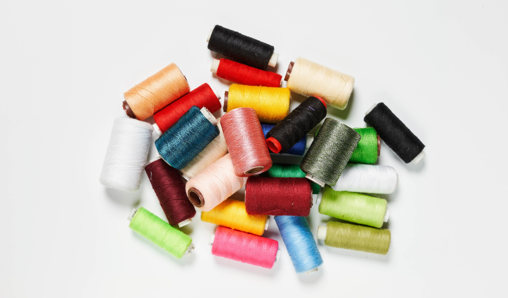 Много катушек разноцветных ниток на белом фоне 