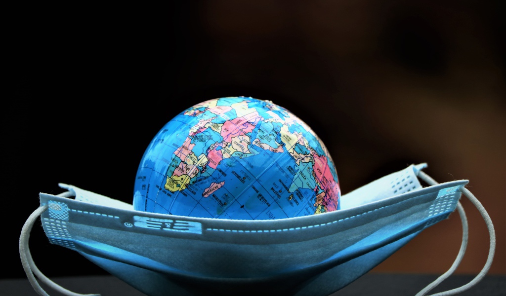 Медицинская маска и глобус на черном фоне