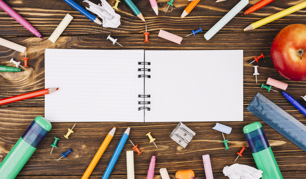 Открытый блокнот с ручками  на столе 