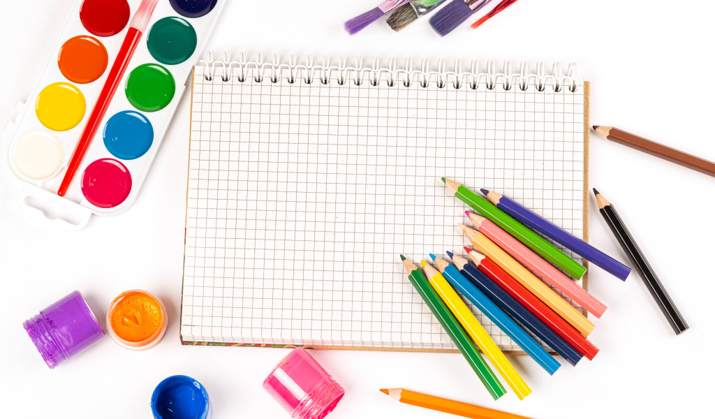 Карандаши, краски и тетрадь на белом фоне 