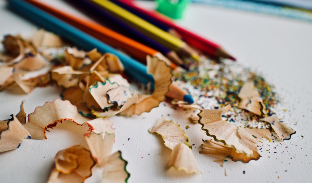 Карандаши со стружкой на сером столе 