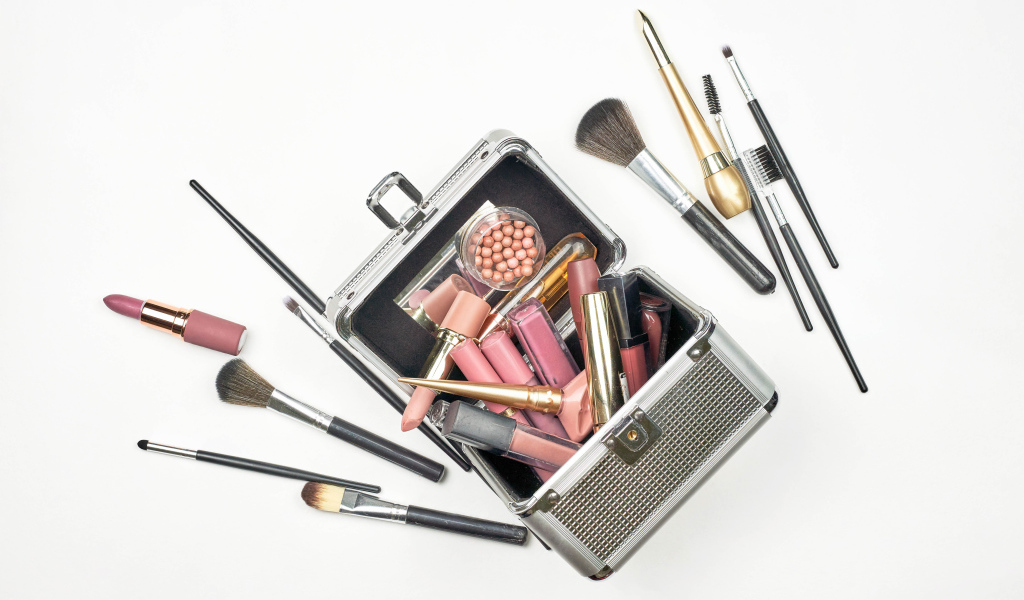Набор косметики в чемодане на белом фоне