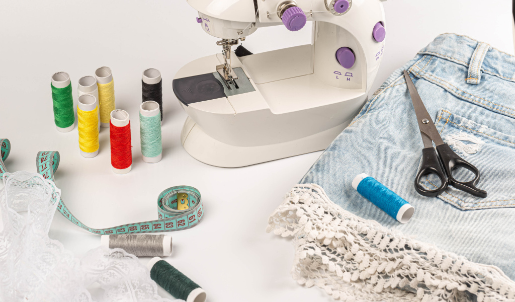 Швейная машинка,юбка и нитки на белом фоне 