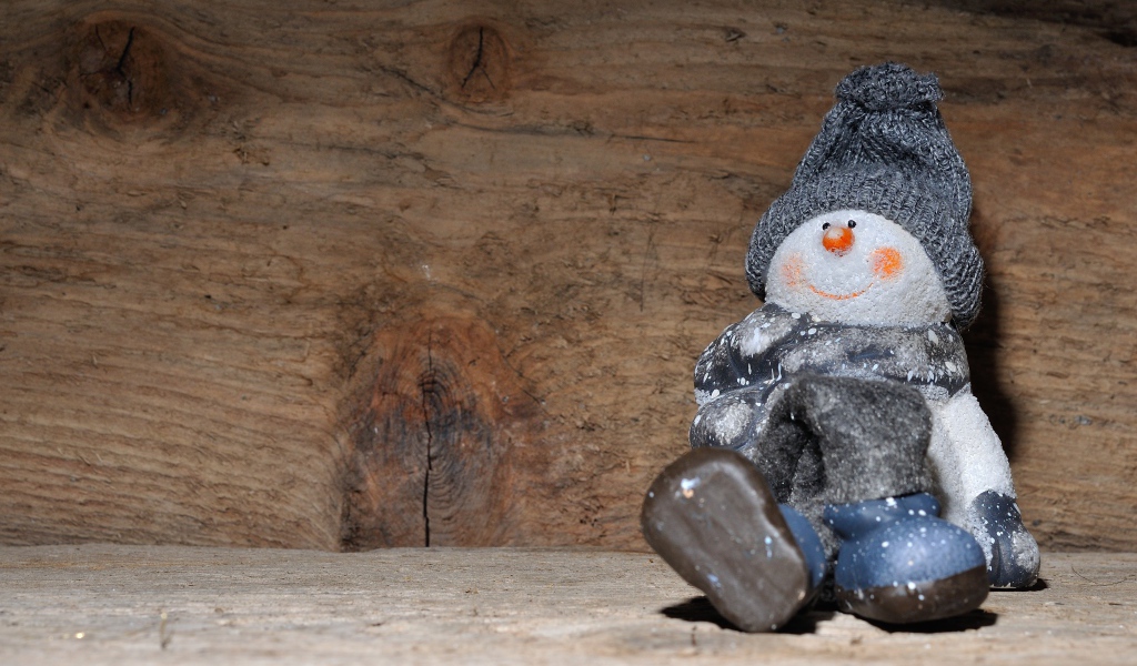 Фигурка снеговик у деревянной стены