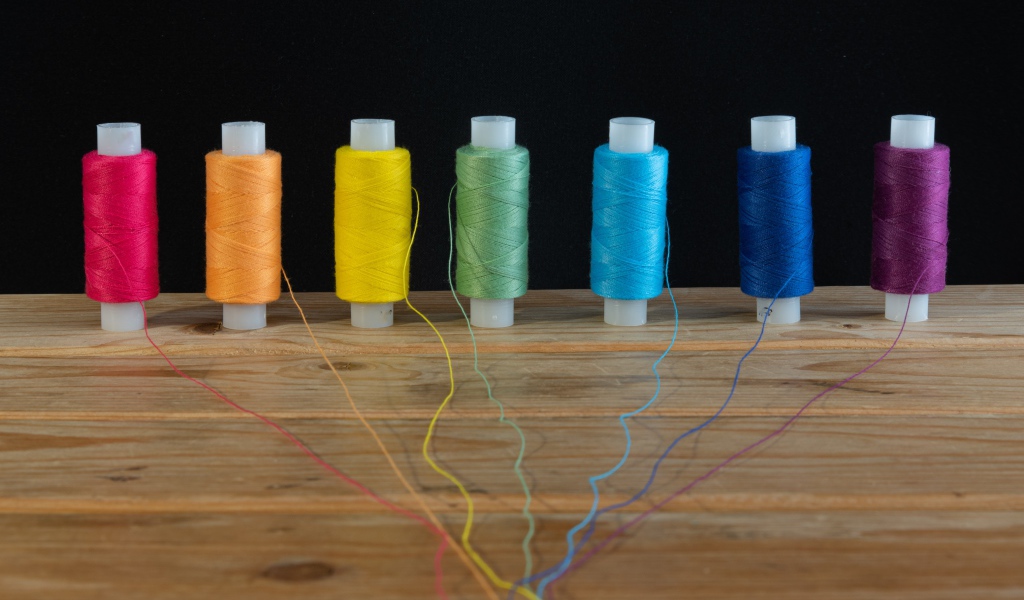 Катушки с разноцветными нитками на черном фоне 