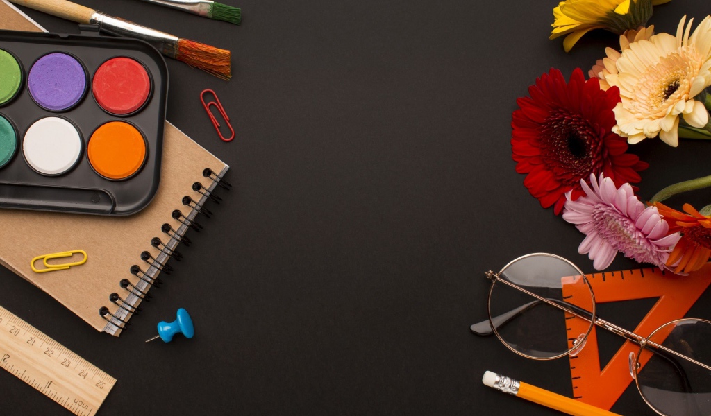 Канцелярские предметы, очки и герберы на черном фоне 