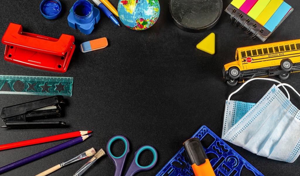 Канцелярские предметы, игрушки и маска на черном столе 