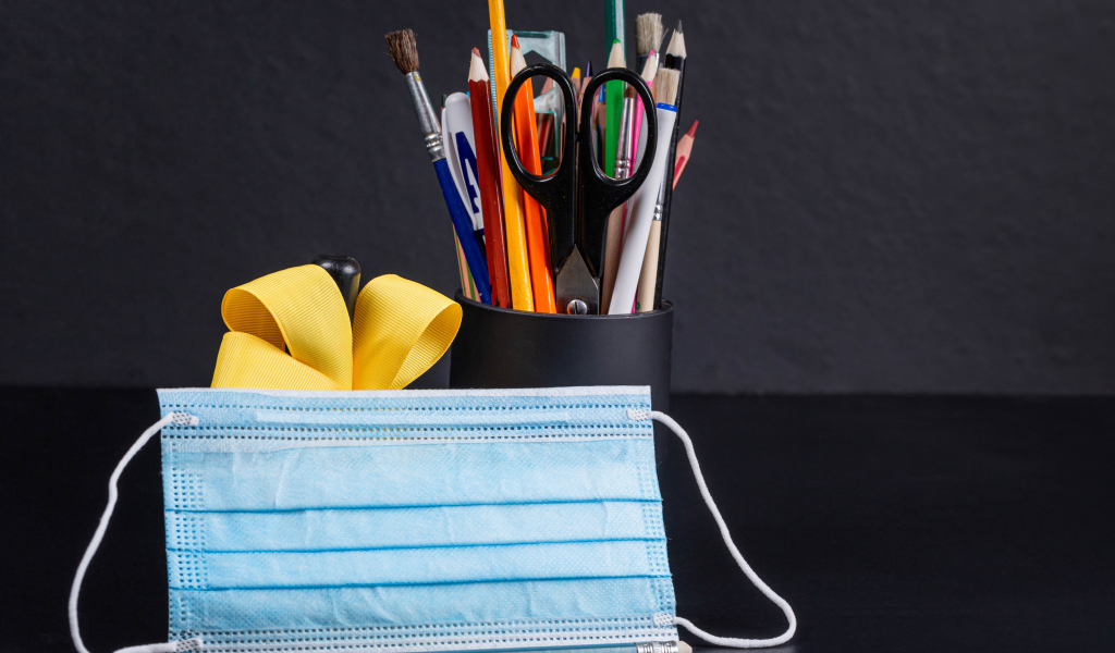 Канцелярские предметы на столе с медицинской маской