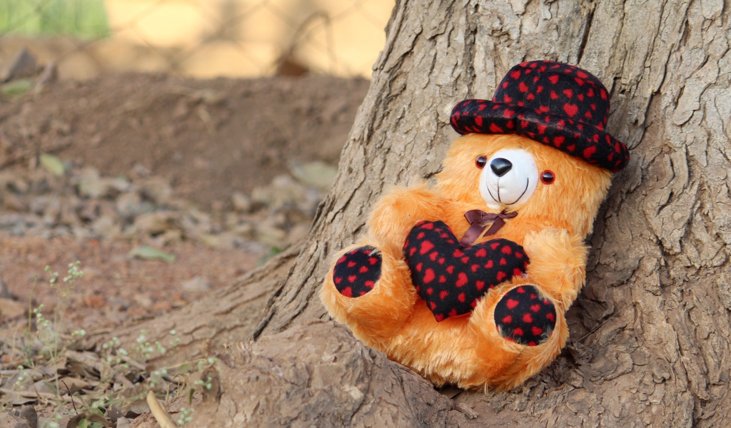 Медвежонок Тедди лежит под деревом