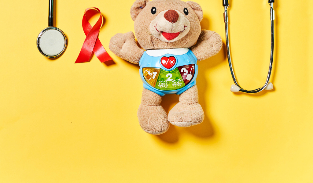 Игрушечный медвежонок с фонендоскопом на желтом фоне 