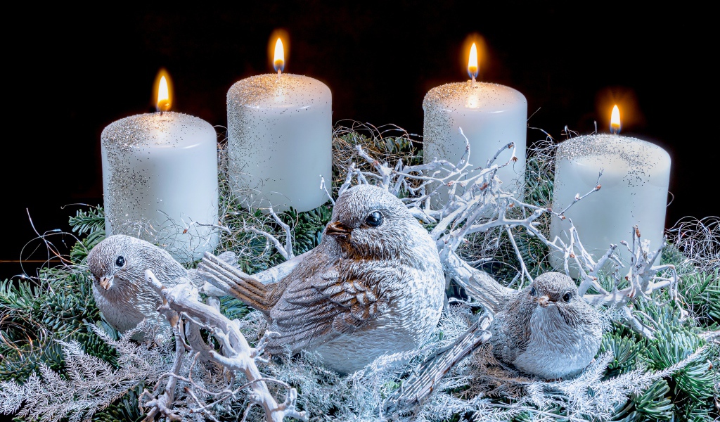 Три зажженные свечи со статуэтками птицами 