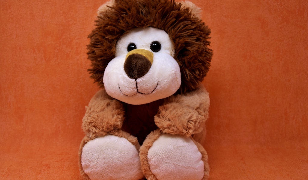 Игрушечный лев на фоне стены