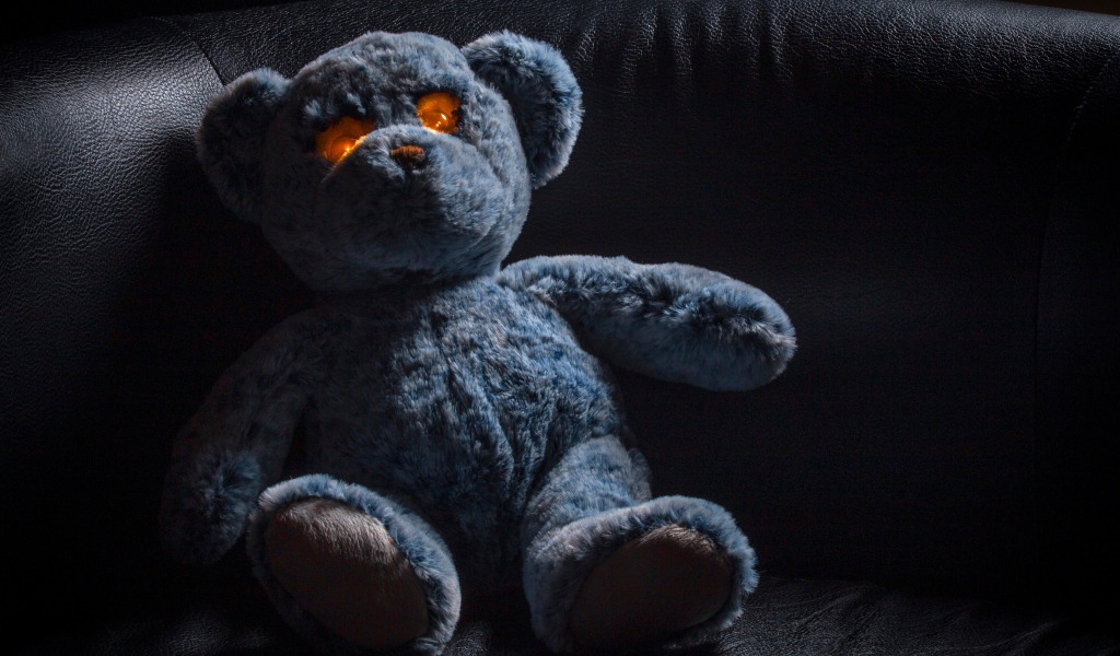 Игрушка со светящимися глазами на черном диване