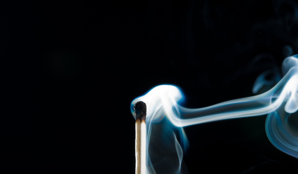 Белый дым от сожженной спички на черном фоне