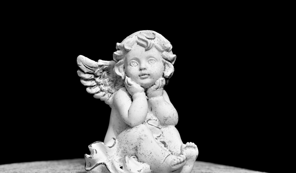 Белая статуэтка ангел на черном фоне