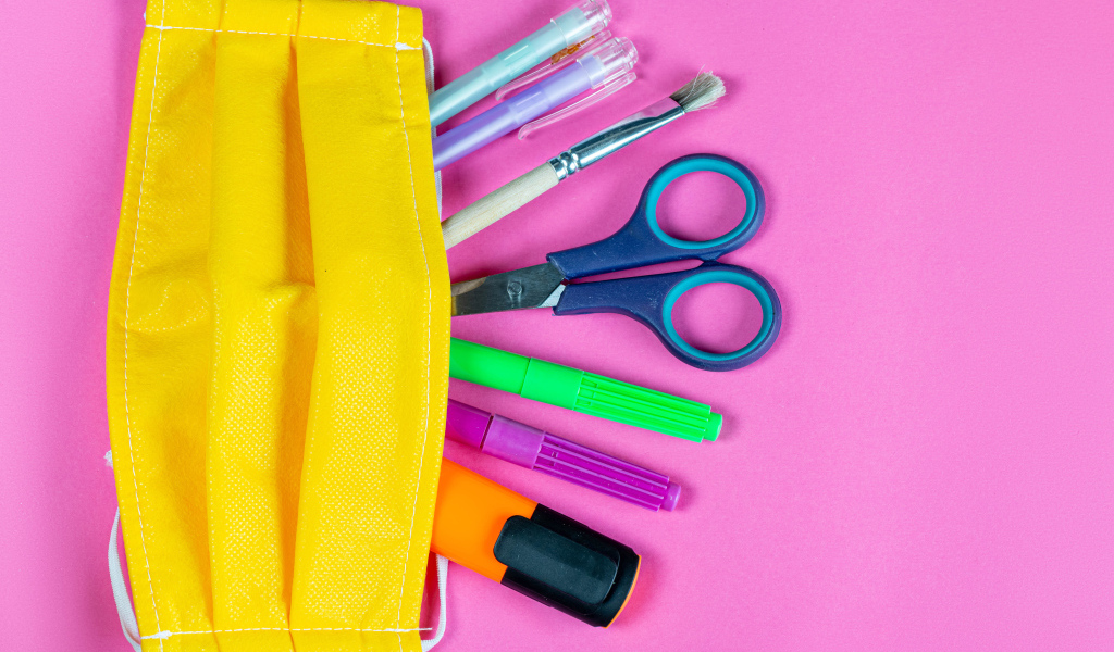 Желтая медицинская маска с ручками и ножницами на  розовом фоне
