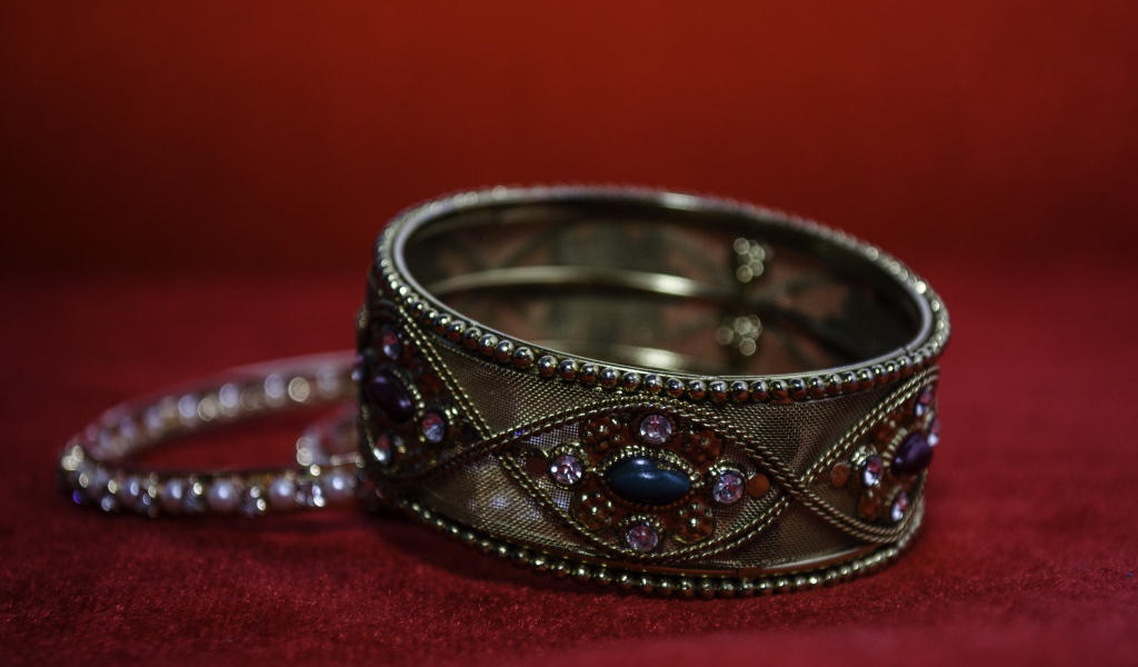 Красивый браслет с драгоценными камнями на красном фоне 