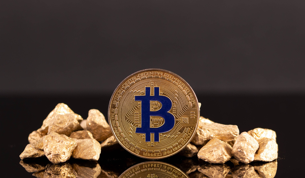 Монета биткоин с кусками золота на сером фоне