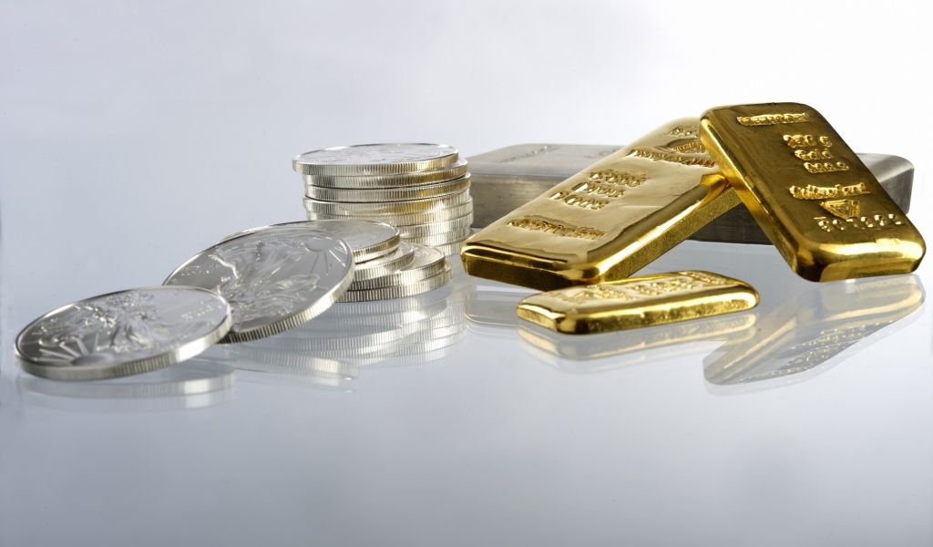 Золотые слитки золота и монеты на белом фоне