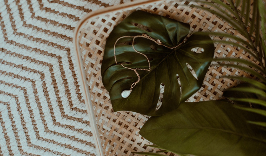 Золотое украшение лежит на большом зеленом листе