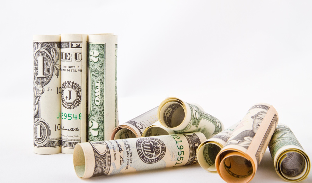 Скрученные в трубочки доллары на белом фоне 