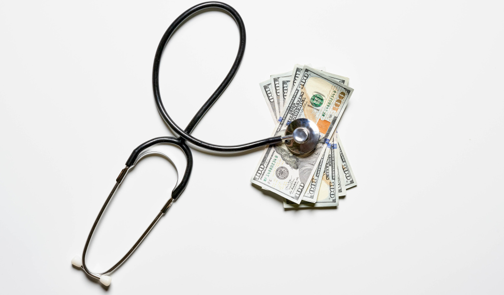 Фонендоскоп с долларами на белом фоне