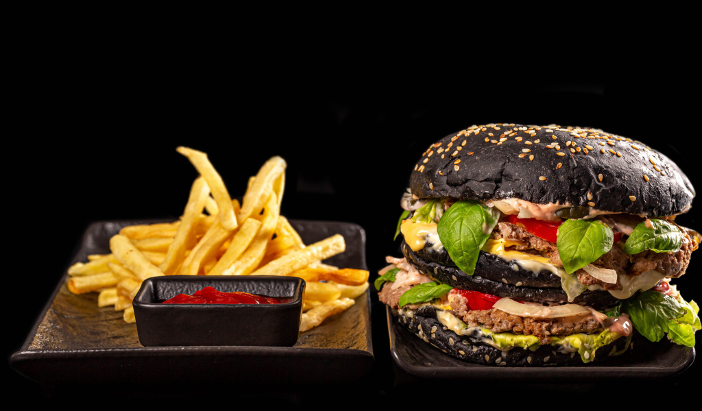 Большой черный гамбургер с картофелем фри и кетчупом 