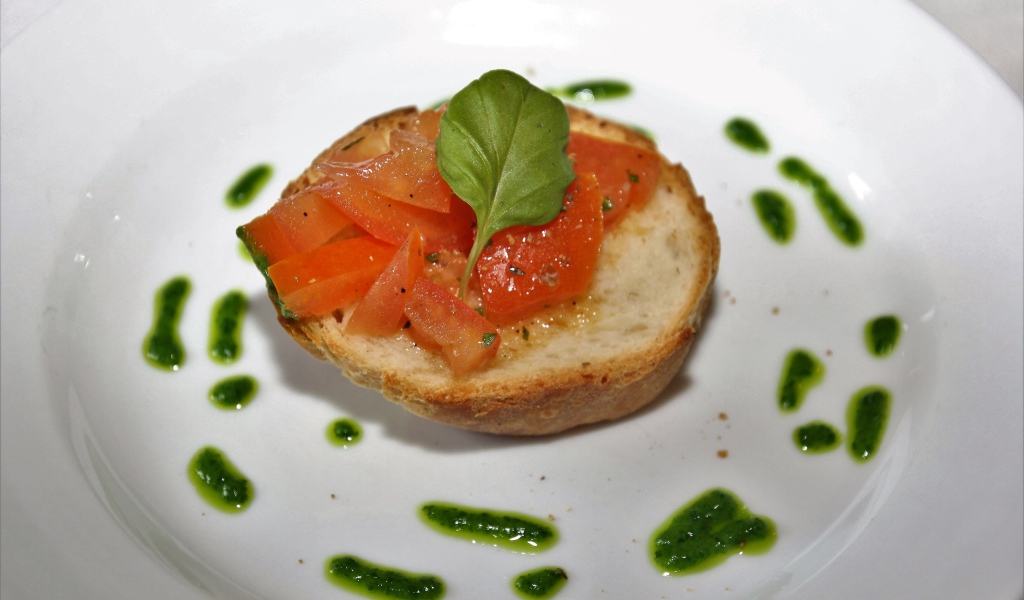 Брускетта на тарелке с помидорами и соусом