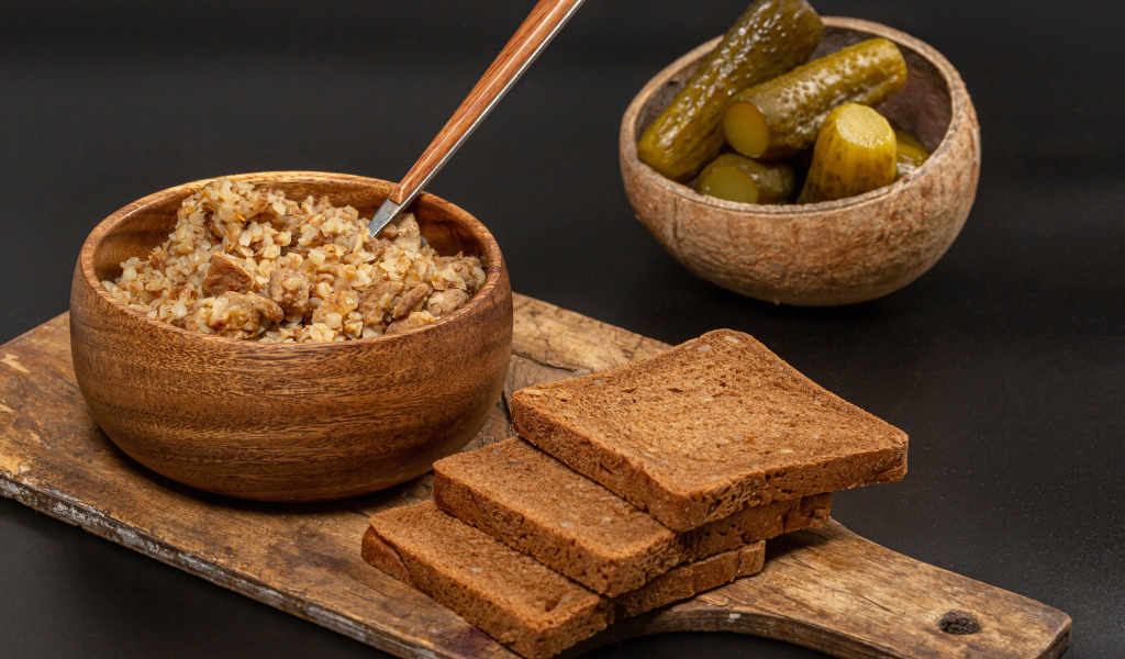 Гречка на столе с хлебом и огурцами